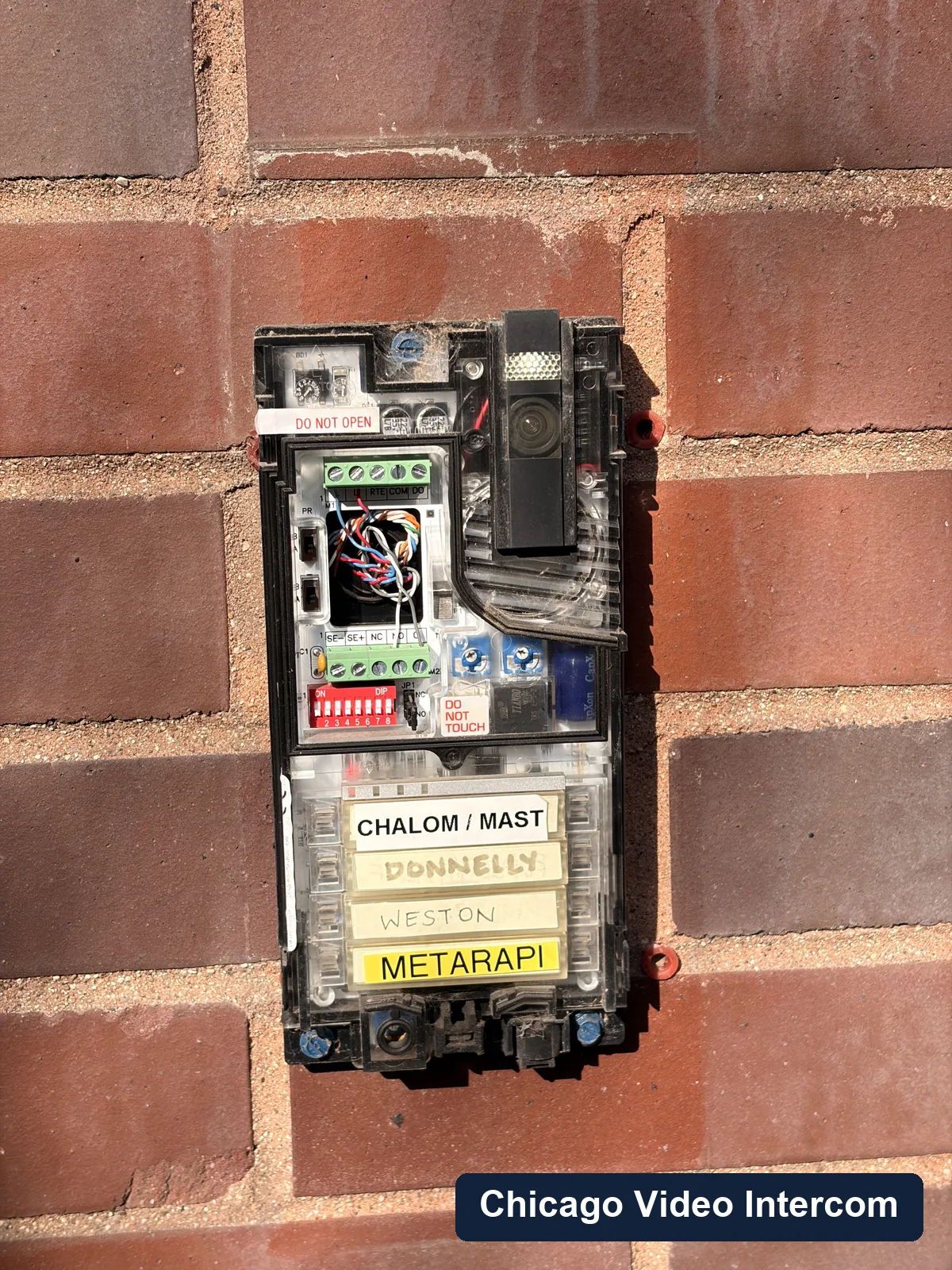 Open older apartment entry panel with wiring and button labels visible