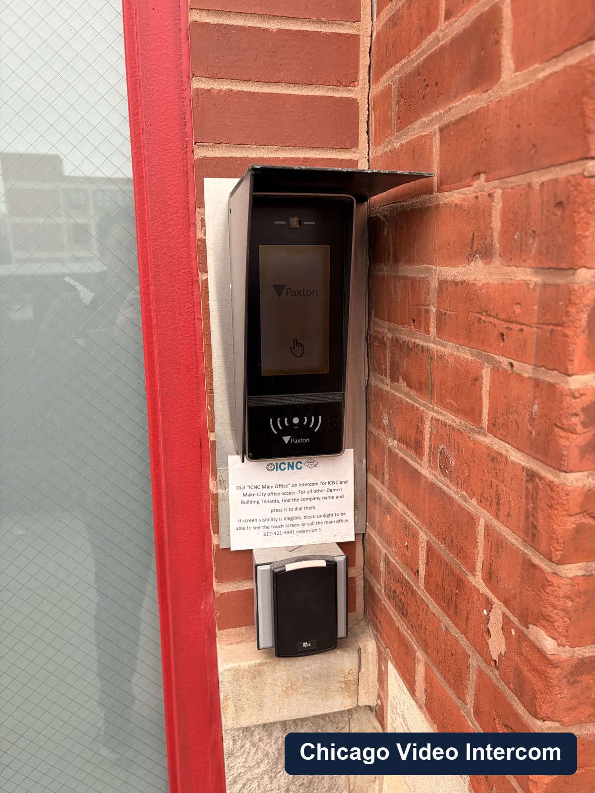 Exterior video entry panel mounted near red trim and brick