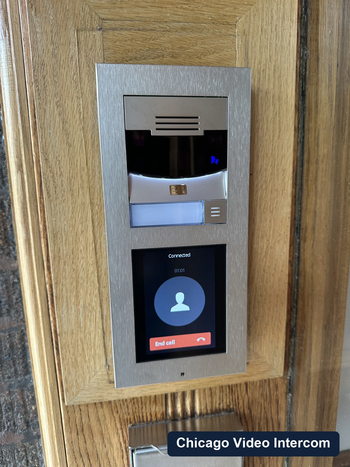 Close-up of video intercom panel mounted in a wood entry frame