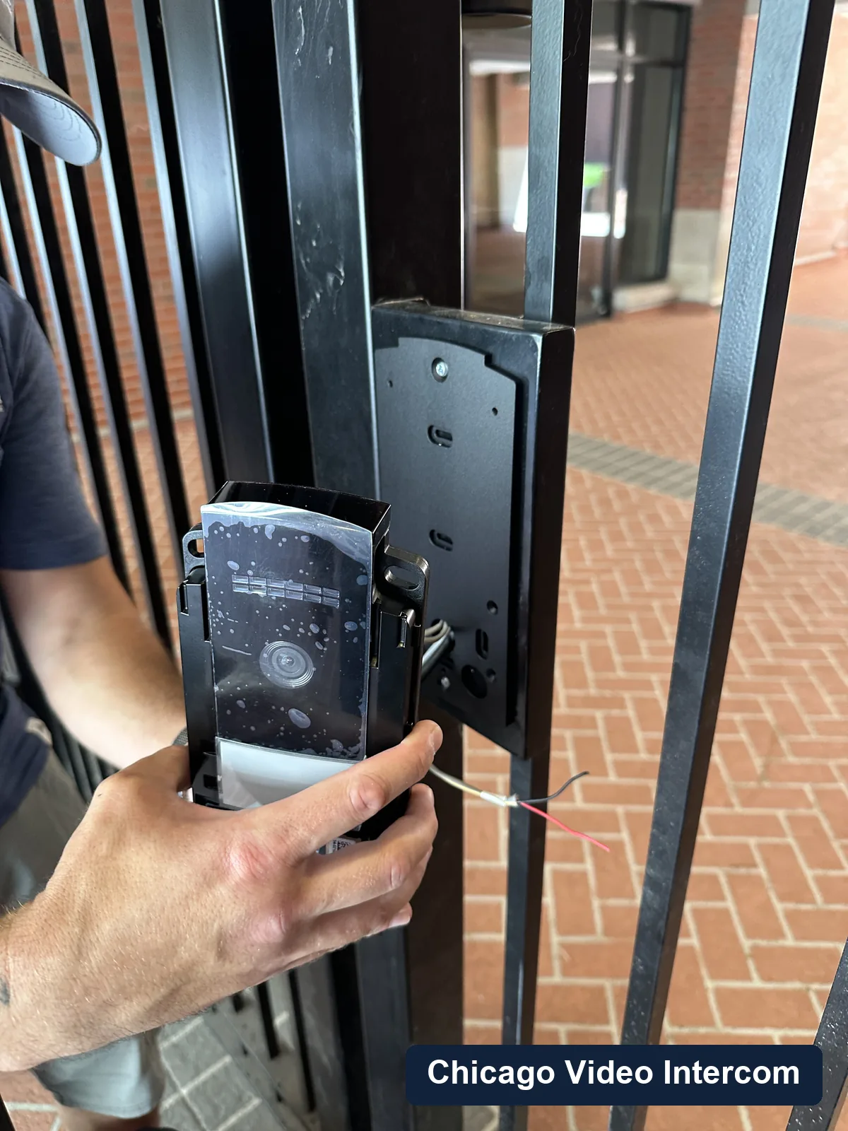 Hands installing a gate intercom panel at a Chicago property